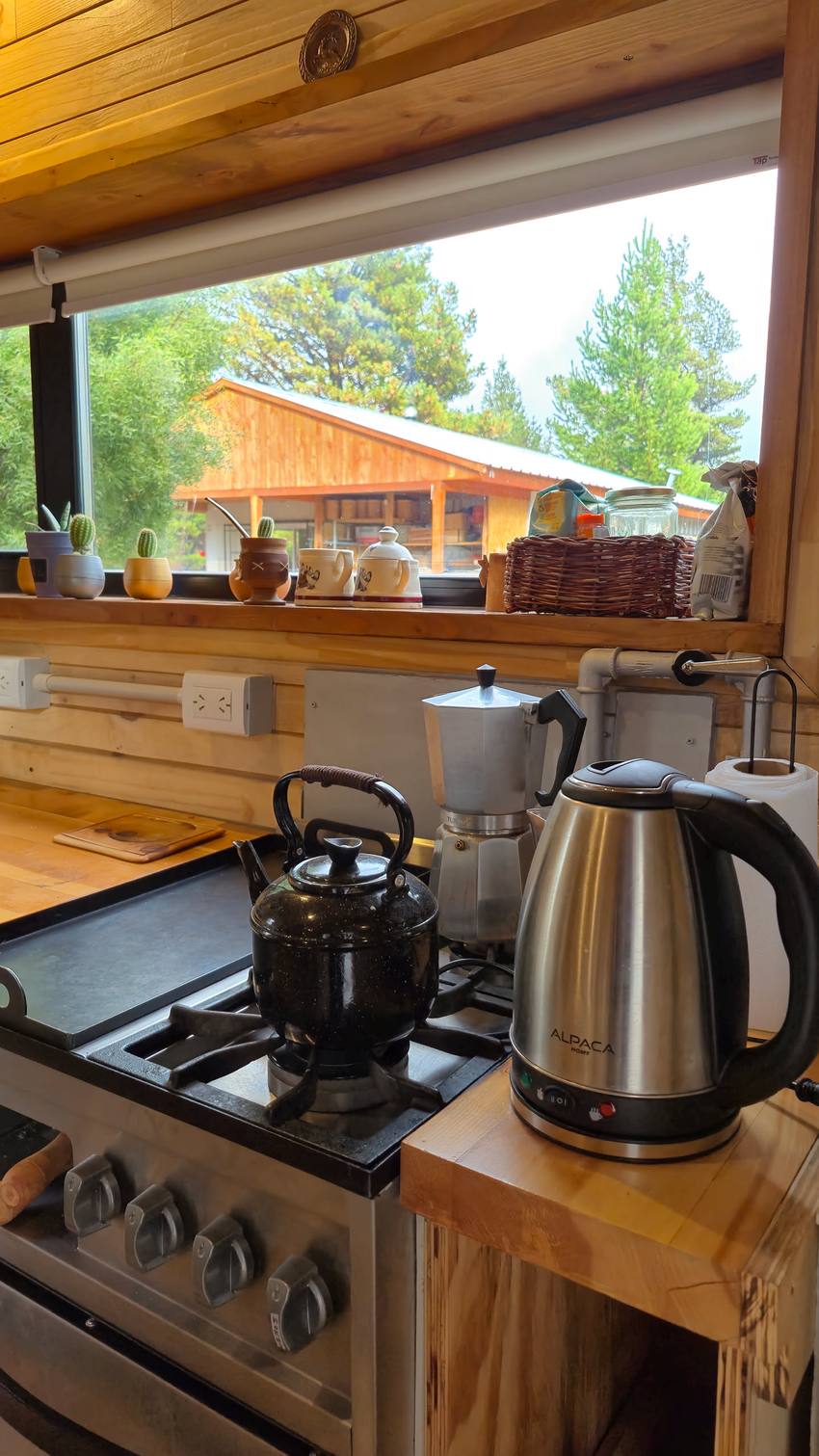 La cocina con pava, cafetera y la ventana al fondo