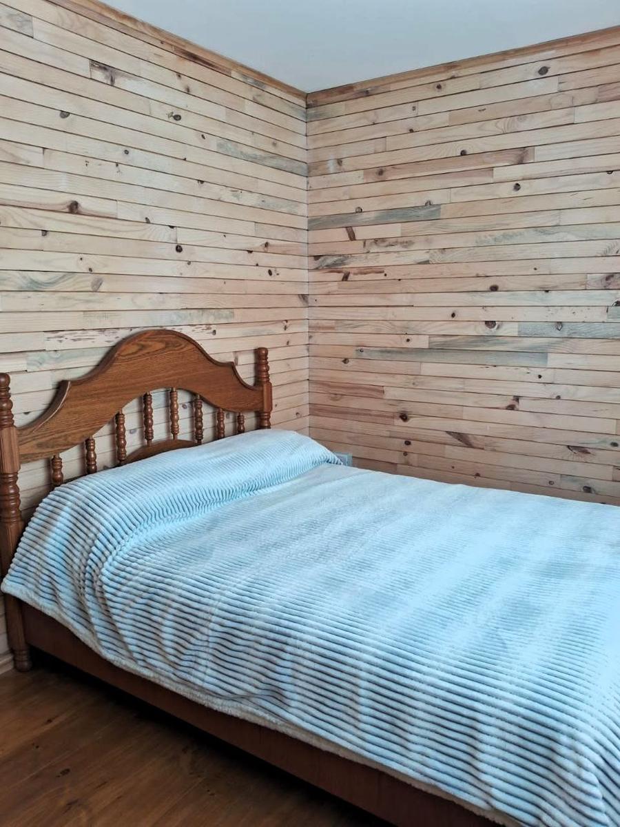 Habitación con cama matrimonial y paredes de madera