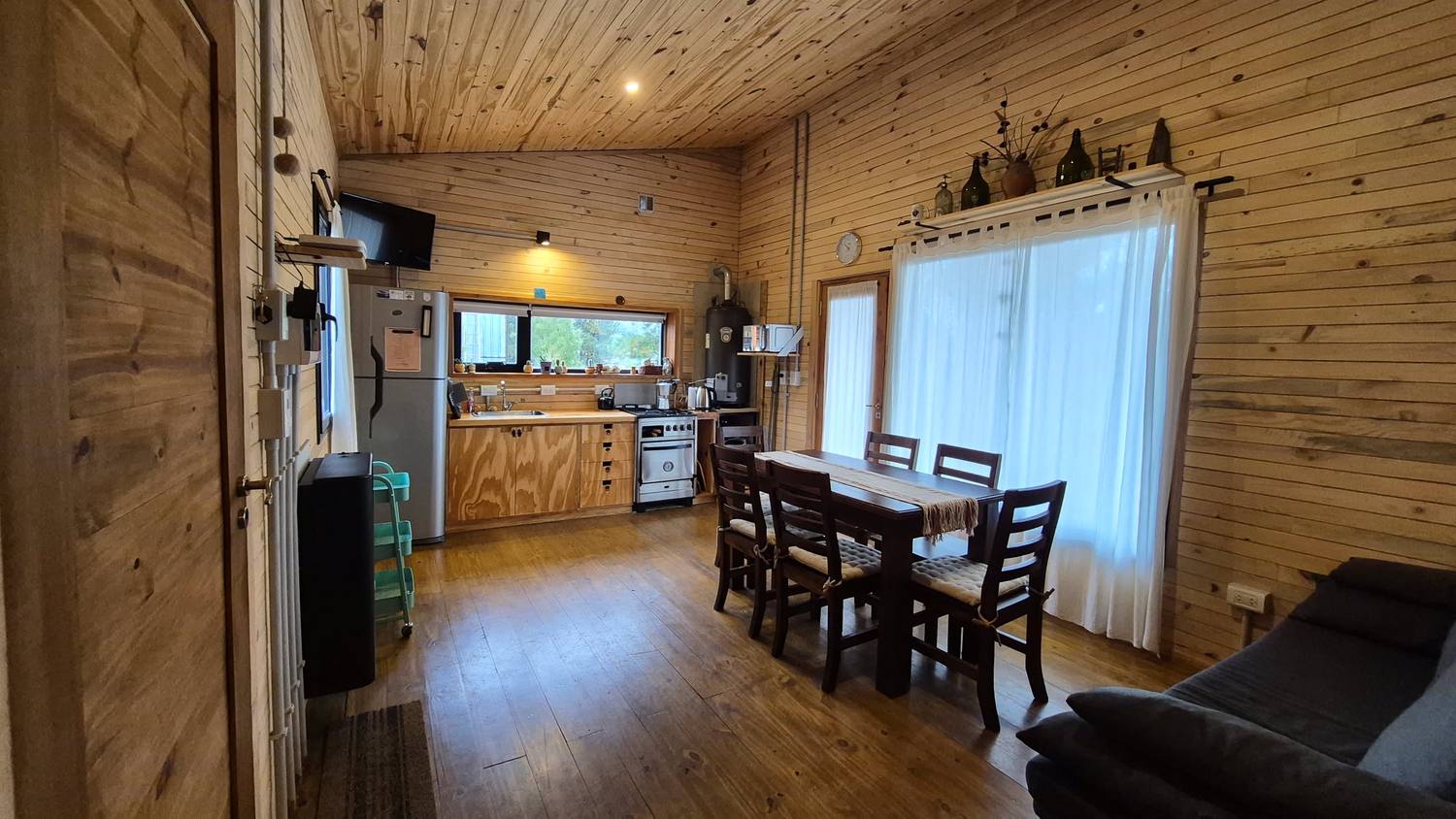 El ambiente principal: cocina de madera, mesa para seis y ventanal al jardín
